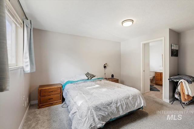 bedroom with light carpet, connected bathroom, and baseboards