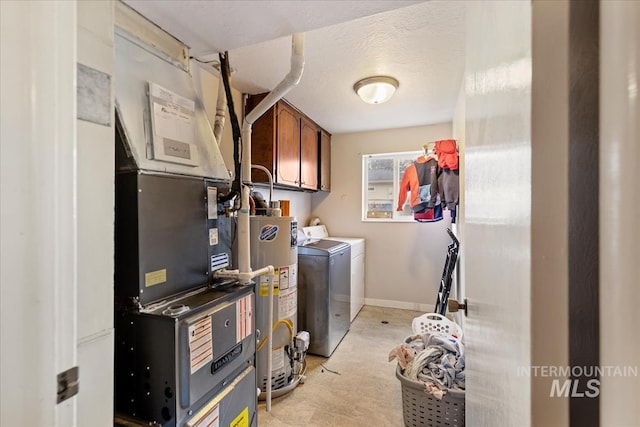 washroom featuring cabinet space, baseboards, washer and clothes dryer, a textured ceiling, and water heater