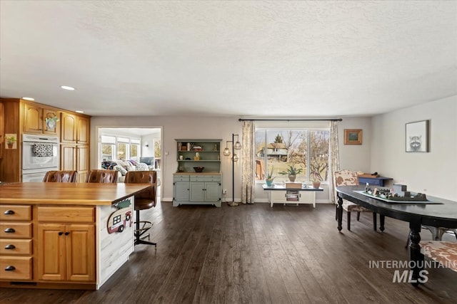 dining area with dark wood-style floors, baseboards, and a textured ceiling