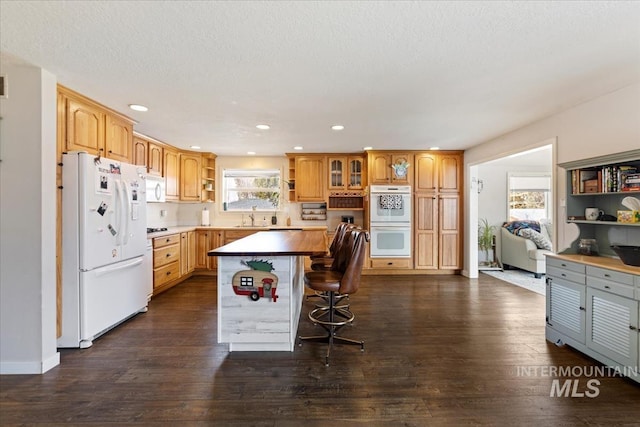 kitchen with white appliances, a breakfast bar, a center island, open shelves, and dark wood finished floors