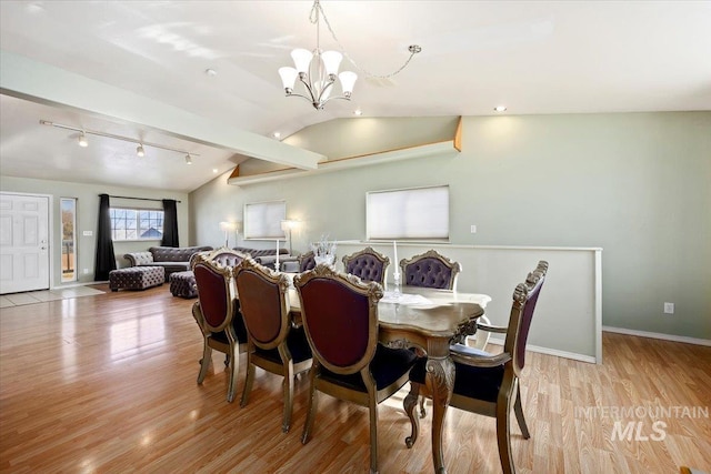 dining room featuring light hardwood / wood-style floors, rail lighting, an inviting chandelier, and vaulted ceiling