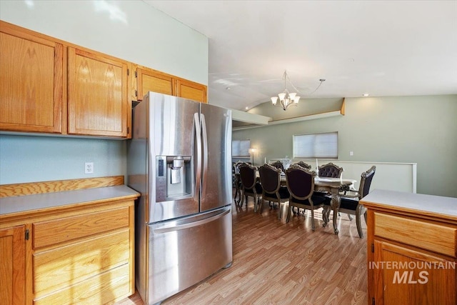 kitchen with vaulted ceiling, light wood-type flooring, stainless steel fridge, and a chandelier