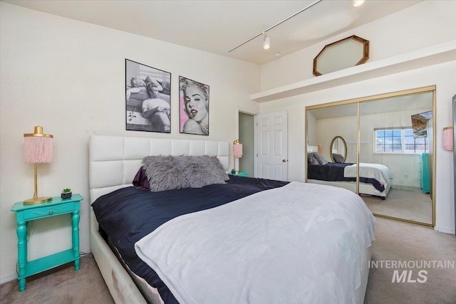 carpeted bedroom with rail lighting and a closet