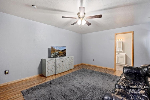 living room featuring light hardwood / wood-style floors, ceiling fan, and a textured ceiling