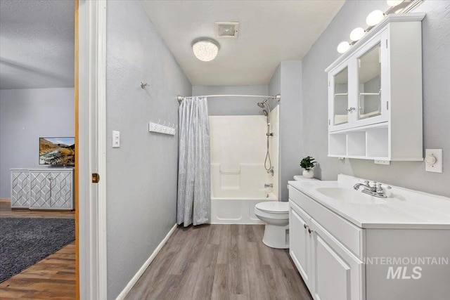 full bathroom featuring toilet, a textured ceiling, hardwood / wood-style flooring, and shower / bath combo with shower curtain