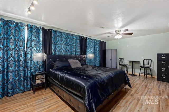 bedroom featuring a textured ceiling, ceiling fan, and light hardwood / wood-style flooring