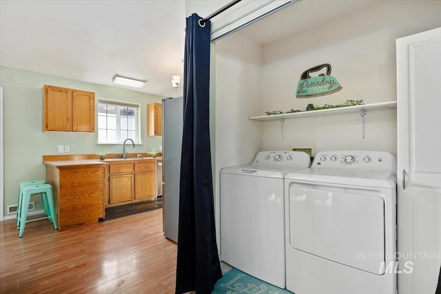 laundry area featuring sink, washing machine and clothes dryer, and light wood-type flooring