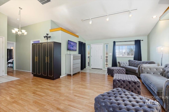 living room with lofted ceiling, a notable chandelier, and light hardwood / wood-style flooring