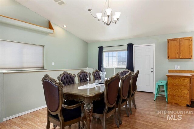 dining room featuring vaulted ceiling, an inviting chandelier, and light hardwood / wood-style floors