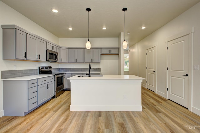 kitchen with light countertops, light wood-style flooring, gray cabinets, and appliances with stainless steel finishes