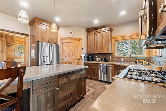 kitchen with appliances with stainless steel finishes, light hardwood / wood-style flooring, backsplash, and decorative light fixtures