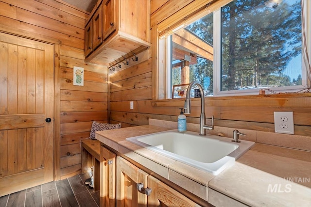 bathroom with a tub, wood-type flooring, sink, and wood walls