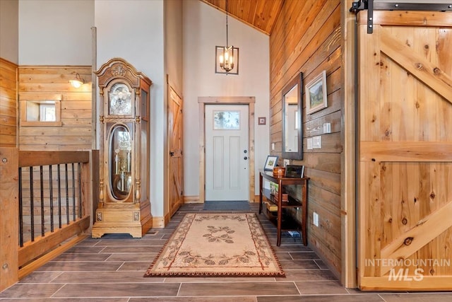 foyer featuring high vaulted ceiling and wood walls