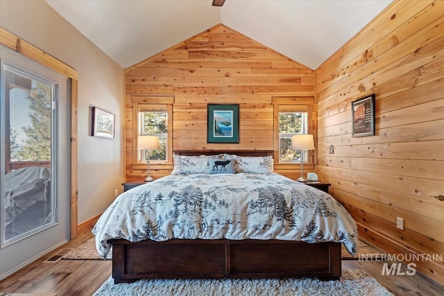 bedroom with lofted ceiling, hardwood / wood-style floors, and wood walls