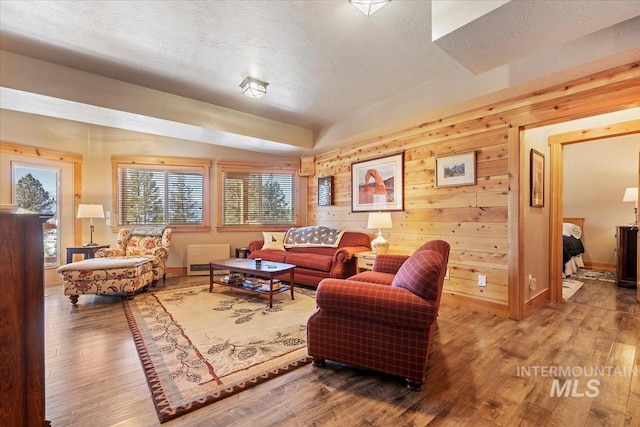 living room with hardwood / wood-style flooring, wooden walls, and a textured ceiling