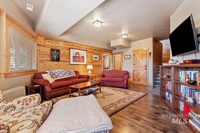 living room with hardwood / wood-style flooring and wooden walls