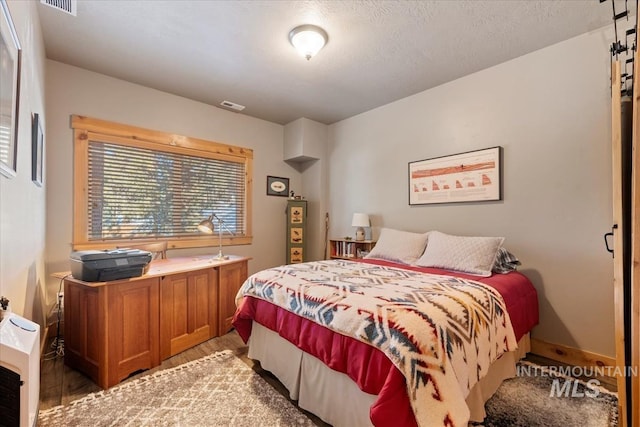 bedroom featuring hardwood / wood-style flooring, a textured ceiling, and heating unit