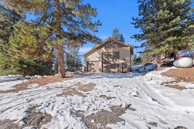 view of snowy exterior featuring a garage and an outdoor structure