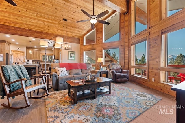 living room featuring ceiling fan with notable chandelier, wood ceiling, wooden walls, and light hardwood / wood-style flooring