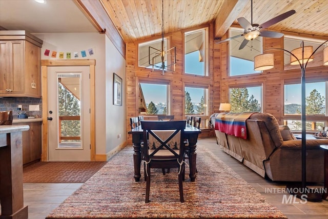 dining room with high vaulted ceiling, wooden walls, beamed ceiling, wood ceiling, and light hardwood / wood-style floors