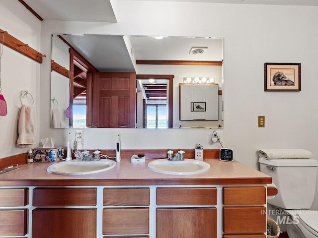 bathroom featuring dual vanity and toilet