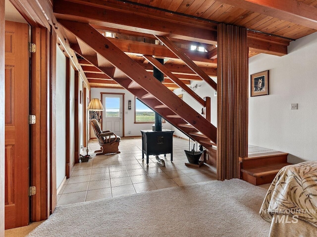 entrance foyer with a wood stove, light tile flooring, and beam ceiling