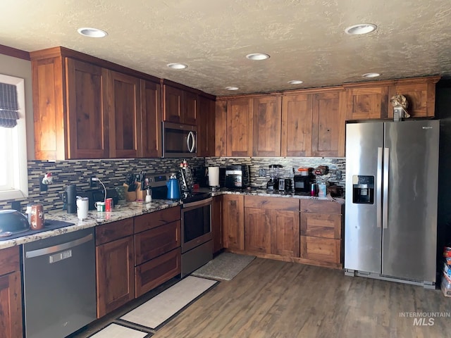 kitchen with light stone counters, appliances with stainless steel finishes, light hardwood / wood-style floors, and tasteful backsplash