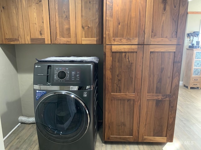 washroom featuring washer / clothes dryer, cabinets, and light hardwood / wood-style floors