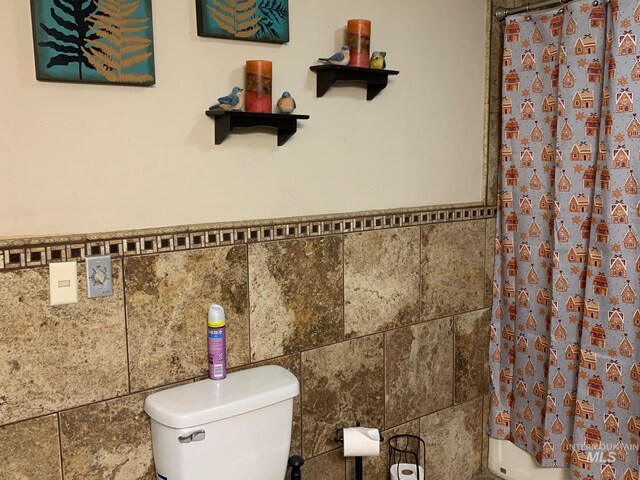 bathroom with tile walls, toilet, and walk in shower