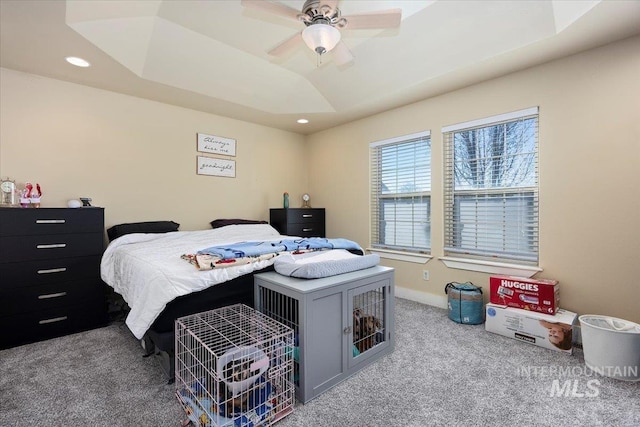 carpeted bedroom featuring baseboards, a raised ceiling, a ceiling fan, and recessed lighting