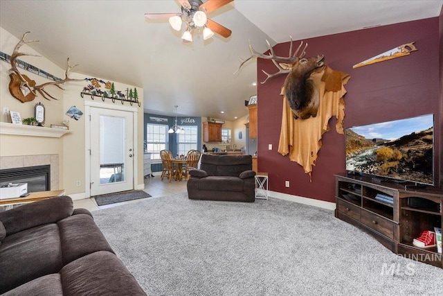 carpeted living room featuring vaulted ceiling, ceiling fan, a fireplace, and baseboards