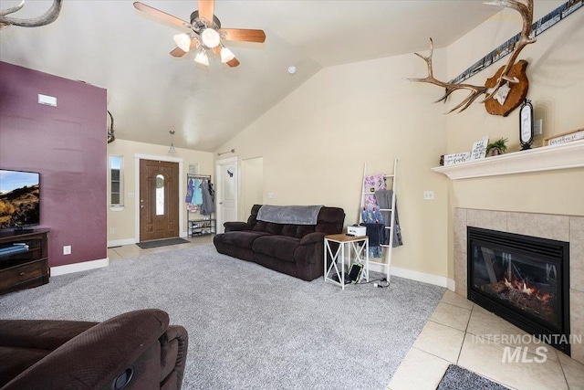 living area with a fireplace, lofted ceiling, ceiling fan, tile patterned flooring, and baseboards