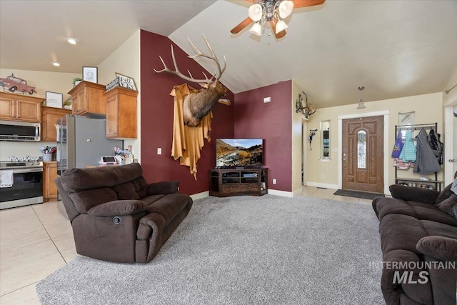 living area with light carpet, light tile patterned floors, baseboards, a ceiling fan, and vaulted ceiling