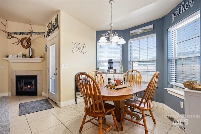 dining room with baseboards, visible vents, a tiled fireplace, tile patterned floors, and a notable chandelier