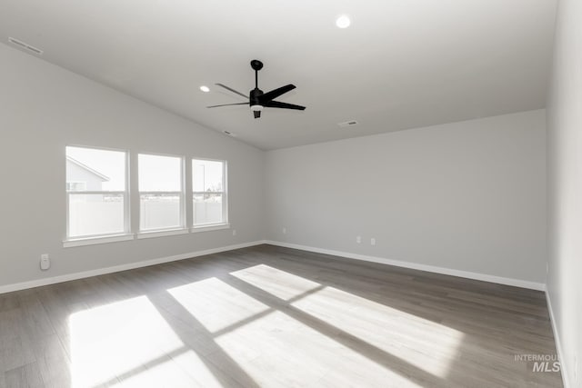 unfurnished room with vaulted ceiling, dark wood finished floors, visible vents, and baseboards