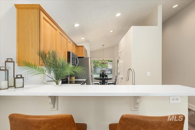 4112 W Cherrytree Ct, Meridian, ID 83642 - kitchen with appliances with stainless steel finishes, recessed lighting, a breakfast bar, a chandelier, and light countertops