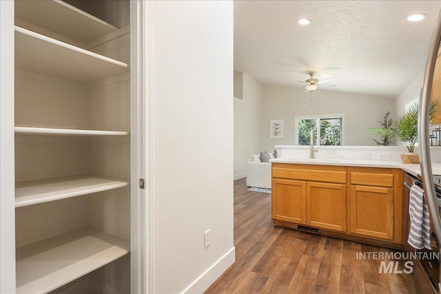 4112 W Cherrytree Ct, Meridian, ID 83642 - kitchen with ceiling fan, a textured ceiling, dark wood-style flooring, a peninsula, and brown cabinetry