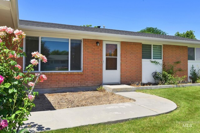 3308 Iowa Ave, Caldwell, ID 83605 - view of front of property with brick siding, a front yard, and roof with shingles