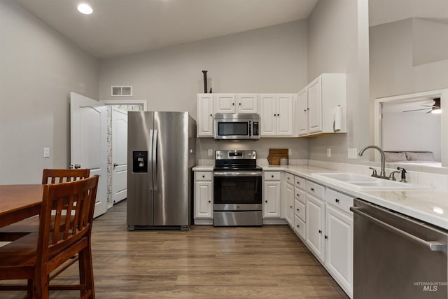 3422 Vistapark Dr, Caldwell, ID 83605 - kitchen featuring stainless steel appliances, a sink, white cabinetry, light countertops, and high vaulted ceiling