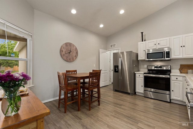 3422 Vistapark Dr, Caldwell, ID 83605 - kitchen featuring stainless steel appliances, high vaulted ceiling, light countertops, white cabinetry, and light wood-style flooring