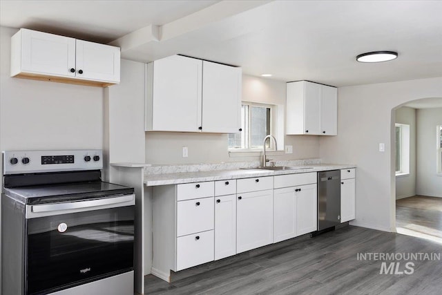 kitchen featuring a sink, light countertops, arched walkways, and appliances with stainless steel finishes