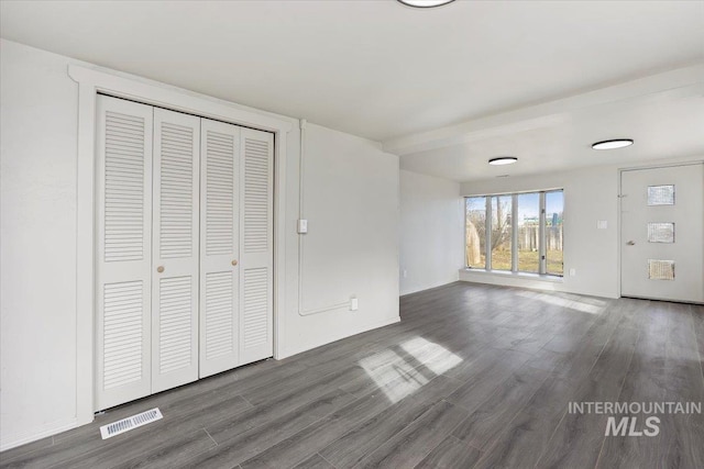 unfurnished bedroom featuring visible vents, a closet, and wood finished floors