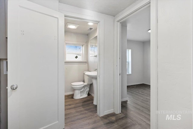 half bathroom featuring toilet, wood finished floors, and baseboards