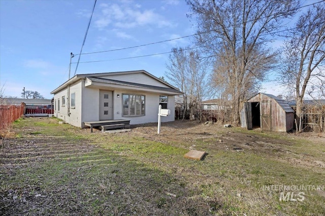 rear view of house featuring a lawn, an outbuilding, fence, and a storage shed