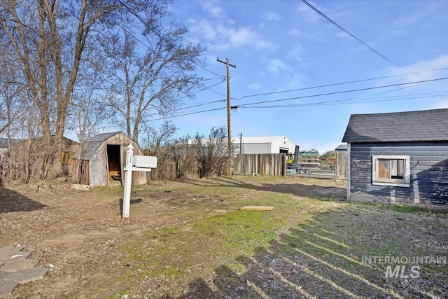 view of yard with an outbuilding, fence, and a storage shed