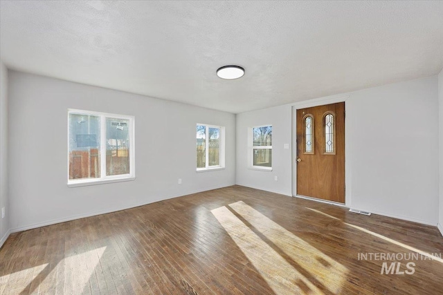 foyer with a textured ceiling, visible vents, and hardwood / wood-style floors