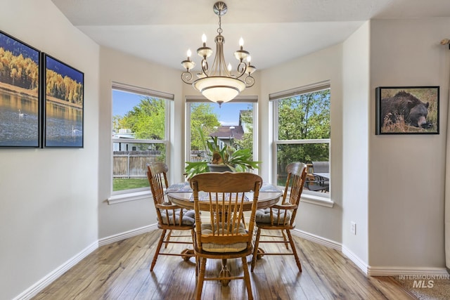 dining room featuring light wood-type flooring, plenty of natural light, a chandelier, and baseboards