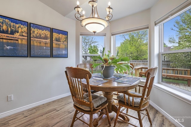dining area featuring plenty of natural light, wood finished floors, a chandelier, and baseboards