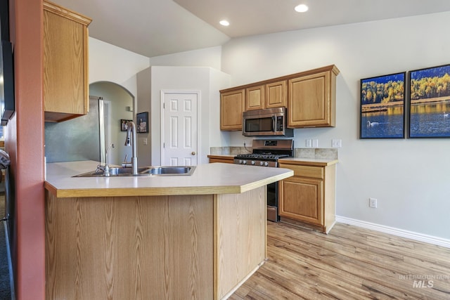 kitchen with appliances with stainless steel finishes, a sink, arched walkways, baseboards, and a peninsula