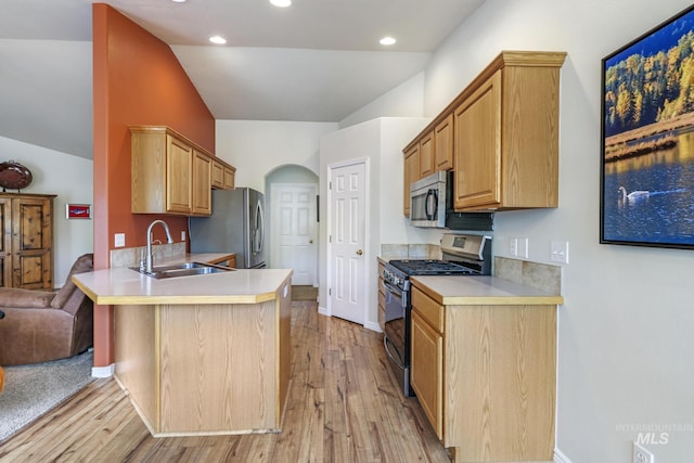 kitchen with stainless steel appliances, a sink, light countertops, a peninsula, and vaulted ceiling